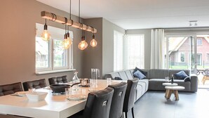 A modern kitchen with a central island, dining area, and a seating area with a sofa and chairs. - Villa With Garden, in a Holiday Park at the Water (Idskenhuizen)