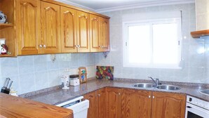 A kitchen with wooden cabinets, a granite countertop, a dishwasher, a stove, and a window. - Belvilla by OYO Villa Josefina (Denia)