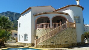 A two-story building with a pool, stone facade, and a balcony with a railing. - Belvilla by OYO Villa Josefina (Denia)