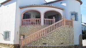 A two-story building with a stone facade, a pink balcony with a balustrade, and a chimney. - Belvilla by OYO Villa Josefina (Denia)