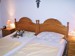 Ein Doppelbett mit blumigen Kissen, ein Nachttisch mit Lampe und einer Uhr.