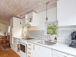 A modern kitchen with white cabinetry, a built-in oven, a stainless steel sink, and a window providing natural light. - 4 Person Holiday Home in Hurup Thy (Hurup Thy)