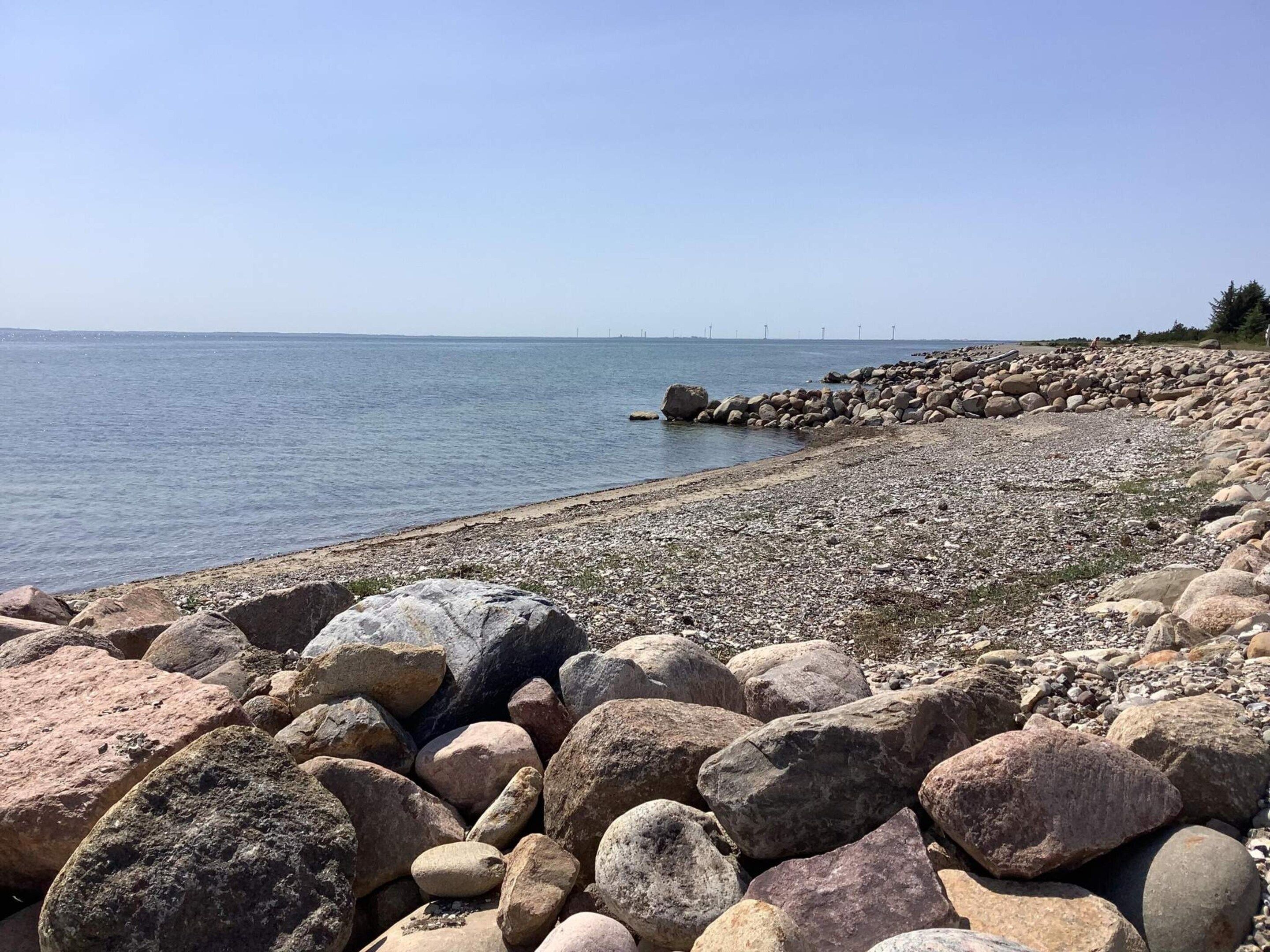 Un littoral rocheux, parsemé de gros blocs de pierre, d’où l’on a une vue dégagée sur la mer.