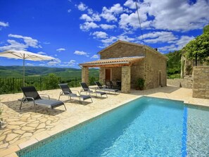 A pool area with lounge chairs and a stone building with a tiled roof. - Alba Comfortable Holiday Residence (Oprtalj)