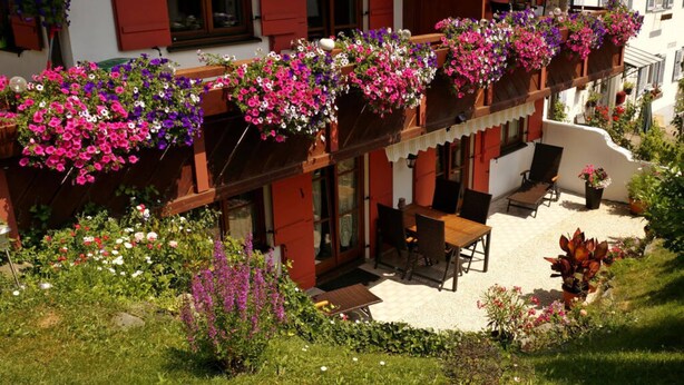A building with a balcony adorned with hanging flower baskets. - Bader Modern Retreat (Blaichach)