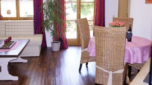 A cozy room with a checkered sofa, a dining table with wicker chairs, a potted plant, and a bottle of wine. - Bader Modern Retreat (Blaichach)