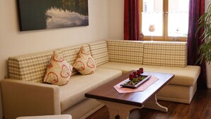 A living room with a sofa, a coffee table with a tray of red berries, and a painting of a lake. - Bader Modern Retreat (Blaichach)