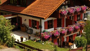 A traditional chalet with a sloped roof, wooden balconies with flower boxes, and a well-maintained garden. - Bader Modern Retreat (Blaichach)