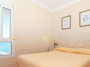 A bedroom with a bed, a nightstand, a lamp, and two framed pictures on the wall. - Belvilla by OYO Apartamento Benal Beach (Benalmádena)