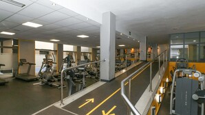 Ένα γυμναστήριο με εξοπλισμό για ασκήσεις, βέλη που υποδεικνύουν την κατεύθυνση στο δάπεδο και μια σκάλα.