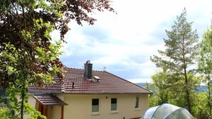 A house with a tiled roof, a small garden, and a blue greenhouse. - Under the District Administrator's Mountain (Treffurt)