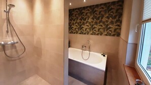 A modern bathroom with a shower, bathtub, and a window providing natural light. - Under the District Administrator's Mountain (Treffurt)