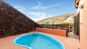 A swimming pool with a stone wall and a view of hills. - Belvilla by OYO Holiday Home in Jandaa (Pajara)