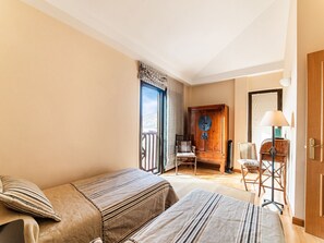 A hotel room with two single beds, a wooden wardrobe, a chair, a table, and a view of the outdoors. - Belvilla by OYO Holiday Home in Jandaa (Pajara)