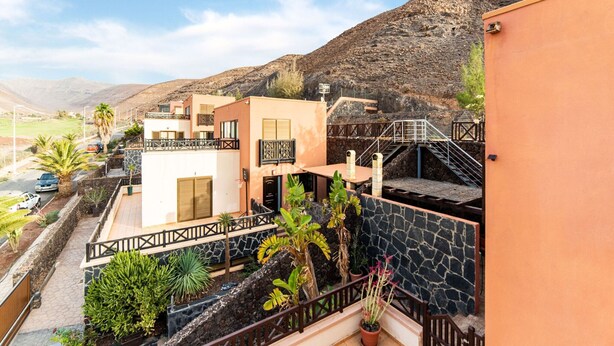 A residential area with modern buildings, a paved road, and a mountainous backdrop. - Belvilla by OYO Holiday Home in Jandaa (Pajara)