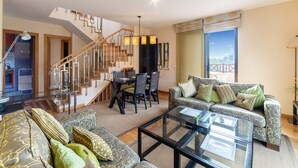 A spacious living room with a staircase, a dining area, and a large window offering a view. - Belvilla by OYO Holiday Home in Jandaa (Pajara)