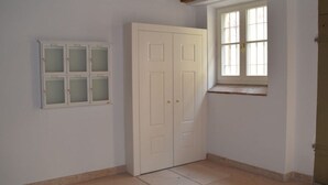 Une pièce avec une armoire blanche, une fenêtre donnant sur un beau paysage et un sol carrelé.