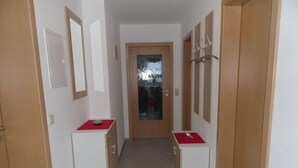 A hallway with two white cabinets, each with a red mat, leading to a door with a frosted glass panel. - Am Reichenbach Modern Retreat (Freiamt)