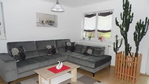 A modern living room with a grey sectional sofa, a wooden coffee table, and a cactus plant. - Am Reichenbach Modern Retreat (Freiamt)