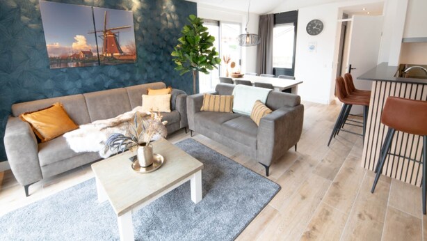 Ein modernes Wohnzimmer mit einem grauen Sofa, einem Couchtisch und einem Essbereich mit einer Bar.