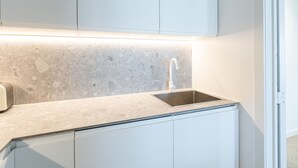 A modern kitchen with a granite countertop, stainless steel sink, and white cabinetry. - Bright Apartment With Direct sea View (Middelkerke)