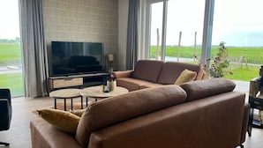 Un salon moderne avec un canapé en cuir, un téléviseur à écran plat et une table basse.