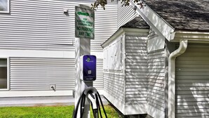 A residential property with a white exterior, a garage, and a charging station for electric vehicles.