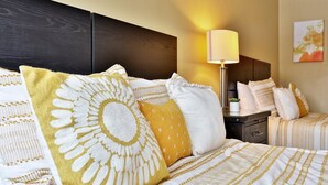 A hotel room with a large bed, a bedside table with a lamp, and a small potted plant.