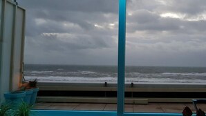 Un balcon avec vue sur l’océan et un ciel nuageux.