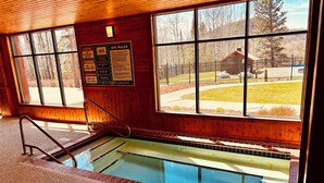 Un espace piscine avec un intérieur en bois, une vue sur l’extérieur et un panneau indiquant les règles du spa.
