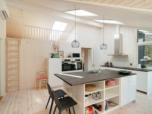 A modern kitchen with a central island, white cabinetry, and pendant lighting. - 5 Star Holiday Home in Hundested (Hundested)