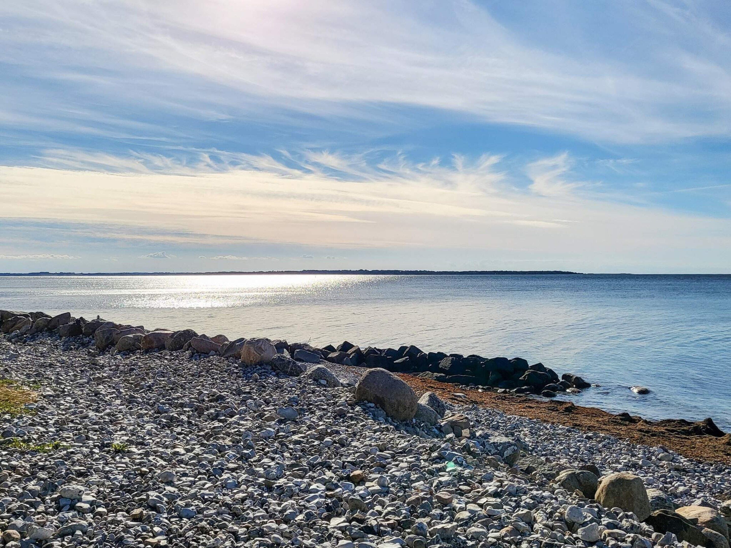A rocky shoreline with a calm sea and a clear sky.