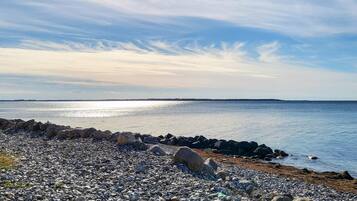 A rocky shoreline with a calm sea and a clear sky.
