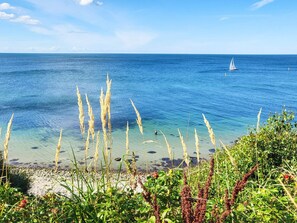 A coastal scene with clear water, a sailboat, and vegetation. - 5 Star Holiday Home in Hundested (Hundested)