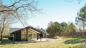 A modern house with a covered patio, a deck, and a fenced yard. - 5 Star Holiday Home in Hundested (Hundested)