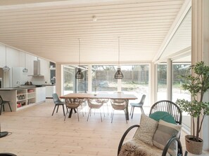 A modern kitchen with a dining area, large windows, and a view of the outdoors.