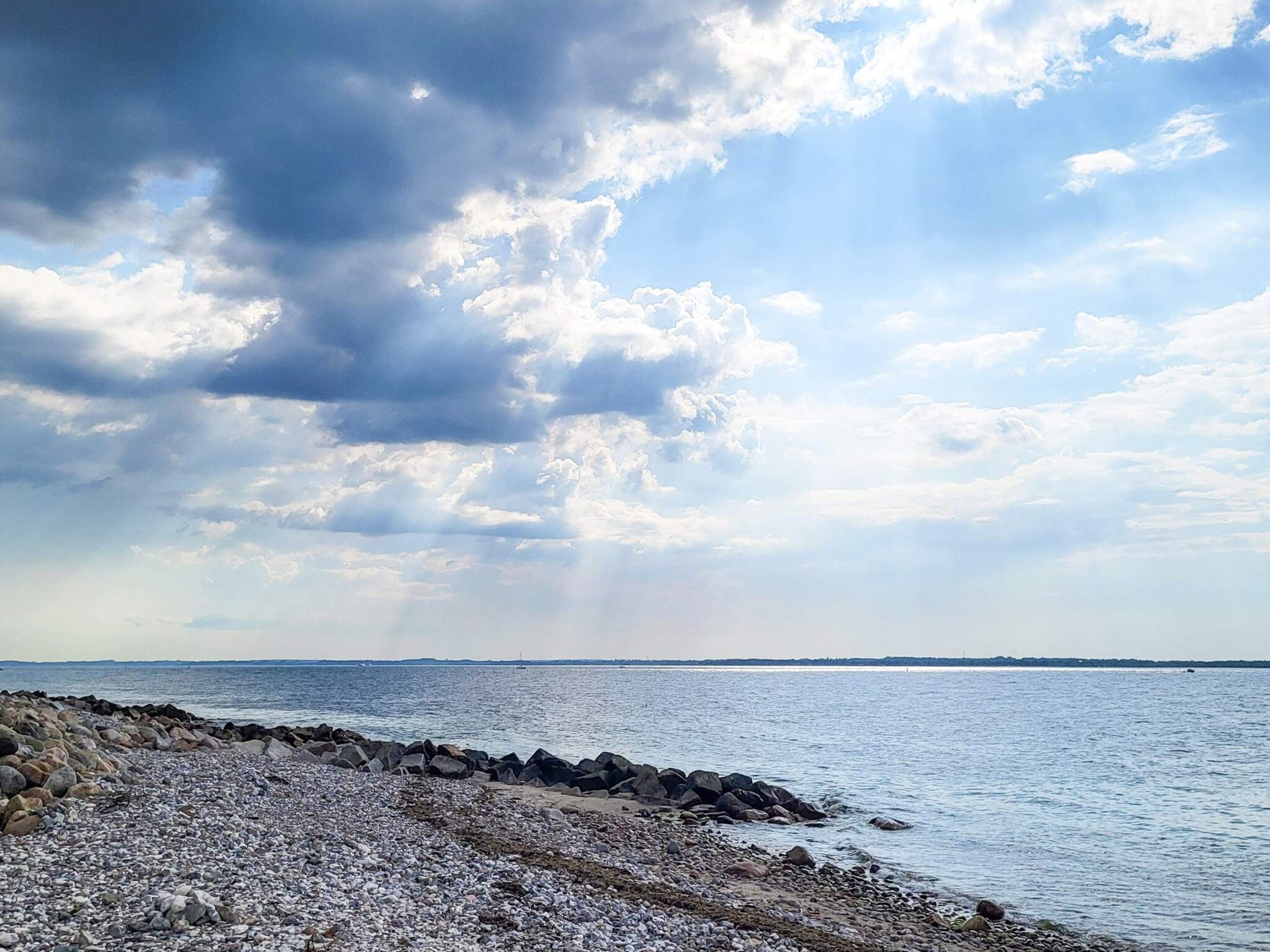 A rocky shoreline with a view of the sea and sky.