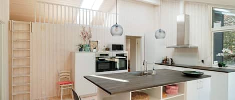 A modern kitchen with a central island, white cabinetry, and pendant lighting.
