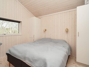 A bedroom with a bed, a window, and wooden walls. - 5 Star Holiday Home in Hundested (Hundested)