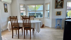 Een eetgedeelte met een ronde tafel, vier houten stoelen en een blauwe bijzettafel met twee vazen.