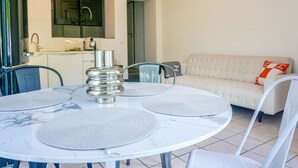 Una sala de estar moderna con un sofá blanco y una mesa de comedor con cuatro sillas.