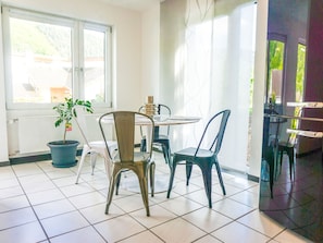 Enjoy meals in this dining area with a table for two, a potted plant, and comfortable chairs.