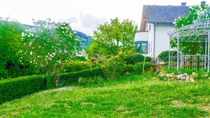 Una casa con jardín, un pabellón de metal y una montaña al fondo.