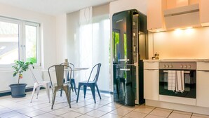 Una cocina moderna con un refrigerador negro, una estufa y un comedor con sillas y una mesa.