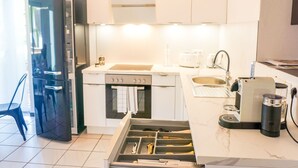 Una cocina moderna con armarios blancos, un refrigerador negro, una estufa y un lavamanos.