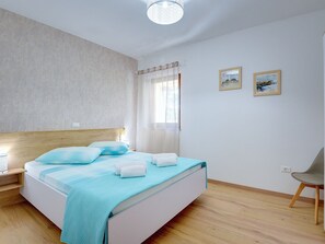 A bedroom with a bed, a nightstand, a chair, and two framed pictures on the wall.