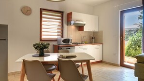 A compact kitchen with a dining area, a microwave, a stove, and a sink. - Apartment in Croatia Near the Coast (Medulin)