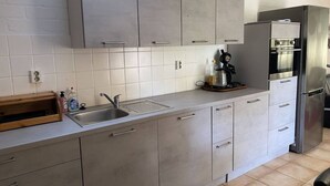 Uma cozinha moderna com armários cinzas, uma geladeira de aço inoxidável e uma cafeteira no balcão.