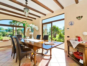 A dining area with a wooden table, chairs, and a vase of white flowers.