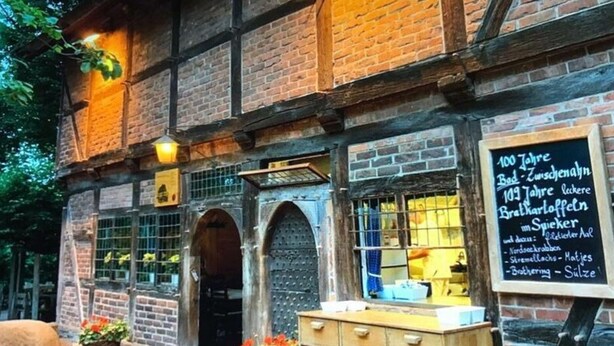 A traditional building with a brick facade, arched doorways, and a wooden bench outside. - Holiday Apartment Summer Breeze (Bad Zwischenahn)